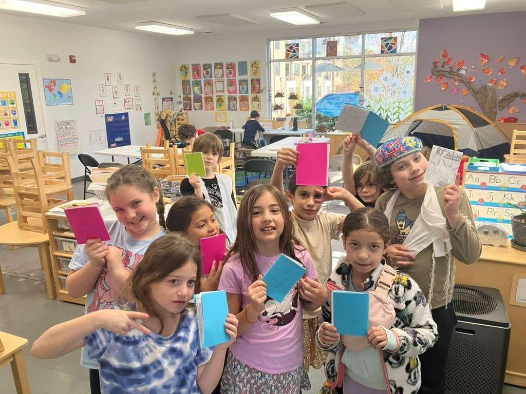 Children holding handmade booklets in class