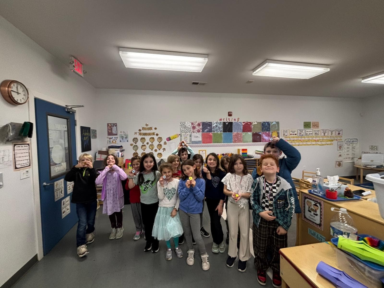 A large group of children holding up craft projects in class